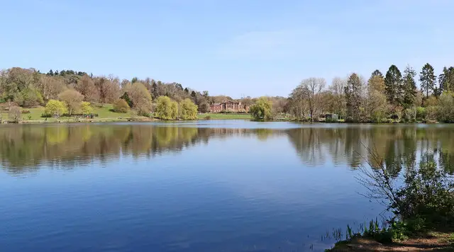 Parkland and a wide lake with a historic hall beyond, typical of the view at Himley Hall and Park in Staffordshire